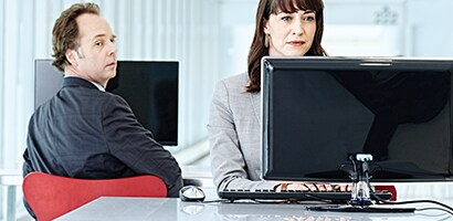 Visuel hacker, der kigger sig over skulderen hen på en skærm
