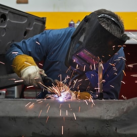 Der flyver gnister, mens en tekniker svejser metaloverflader sammen på en fabrik