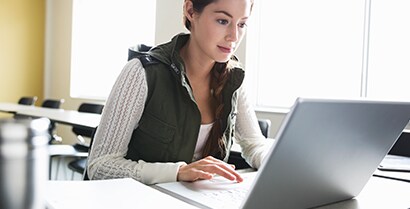 En studerende arbejder på sin bærbare computer i nærheden af ​​et naturligt lys ved hjælp af 3M's bæredygtige sidelysningsfilm.

