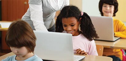 Børn i et klasseværelse med bærbare computere
