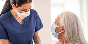 Clinician wearaing PPE talking to patient wearing PPE
