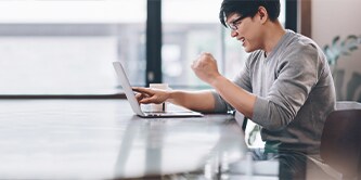 Mand, der sidder i et rum og arbejder på en bærbar computer
