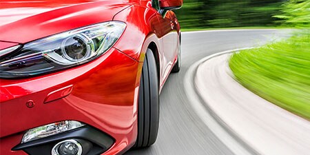 Bil, der drejer rundt i et sving, monteret med røde 3M Vehicle wraps og trims.

