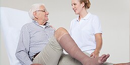 Kliniker, der taler med patient, som er i kompressionsbehandling
