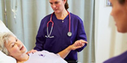 Sygeplejerske ser til en ældre patient
