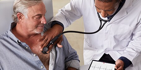Læge, der holder 3M Littmann CORE digital stetoskop mod en mands bryst

