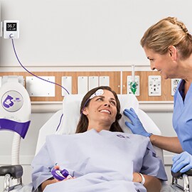 En sygeplejerske ser til en patient i hospitalsseng