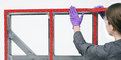 Tekniker anvender industriel tape på en samling mellem paneler og rammer
