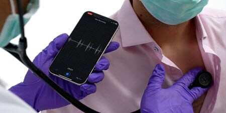 kliniker, der bruger Littmann digitalt stetoskop på en patients bryst og gennemgår live data
