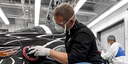 Billede viser en mand, der bruger premium slibemidler med premium værktøj på en bil for at opnå fremragende resultater.
